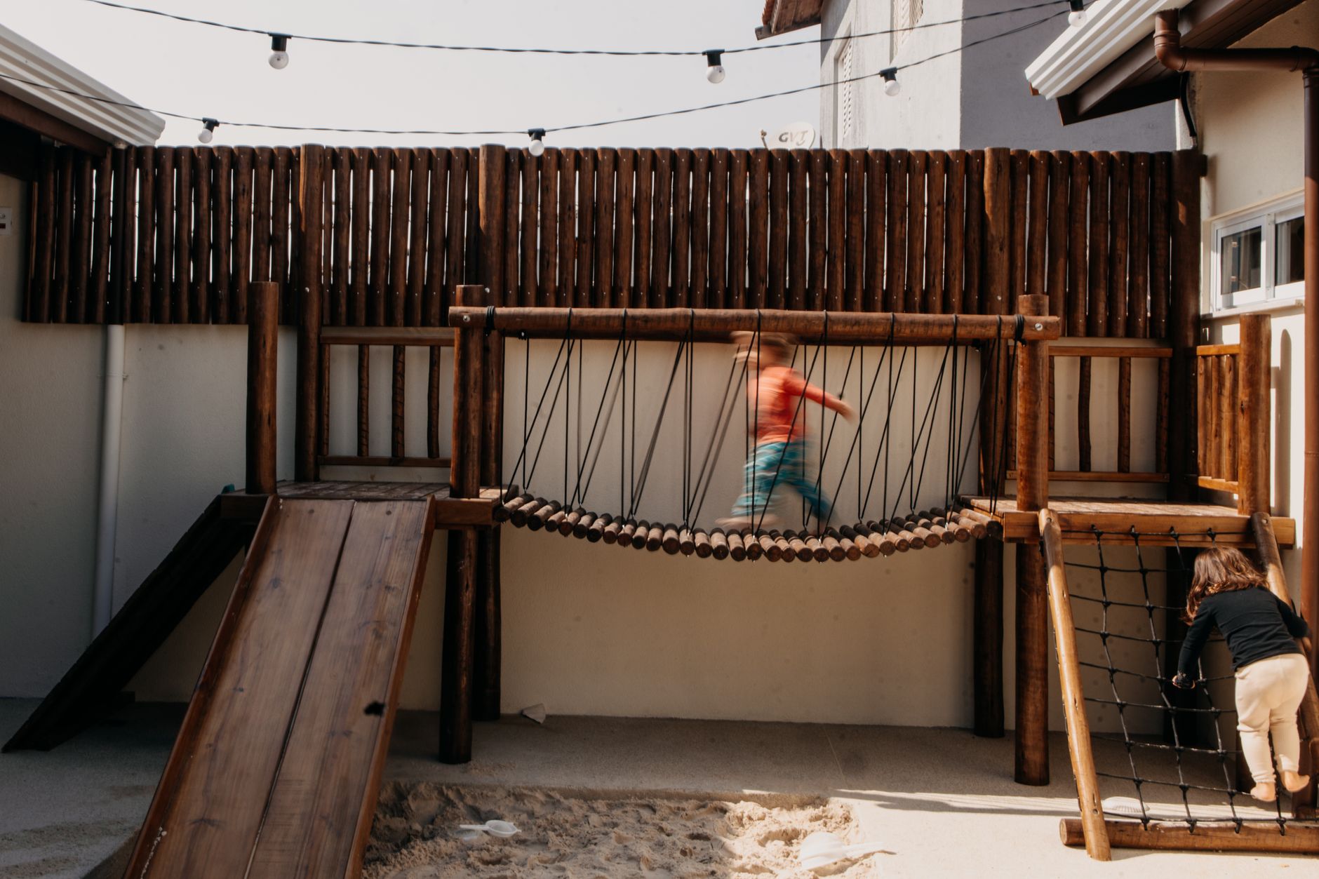 Kids enjoying a wooden playground with slides and ropes. Perfect for outdoor activities and fun.