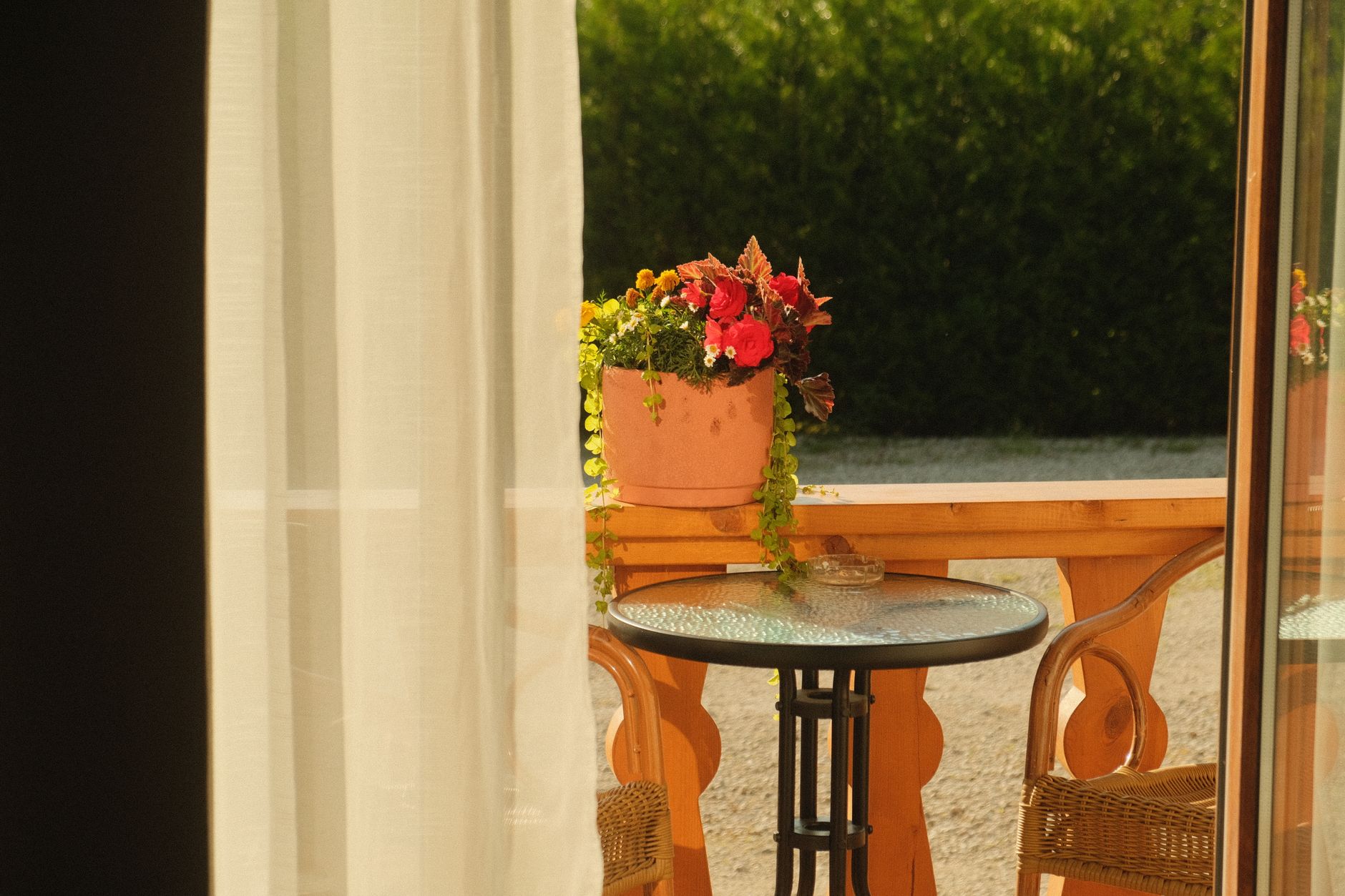 Cozy outdoor patio with potted flowers, wicker chairs, and a round table.