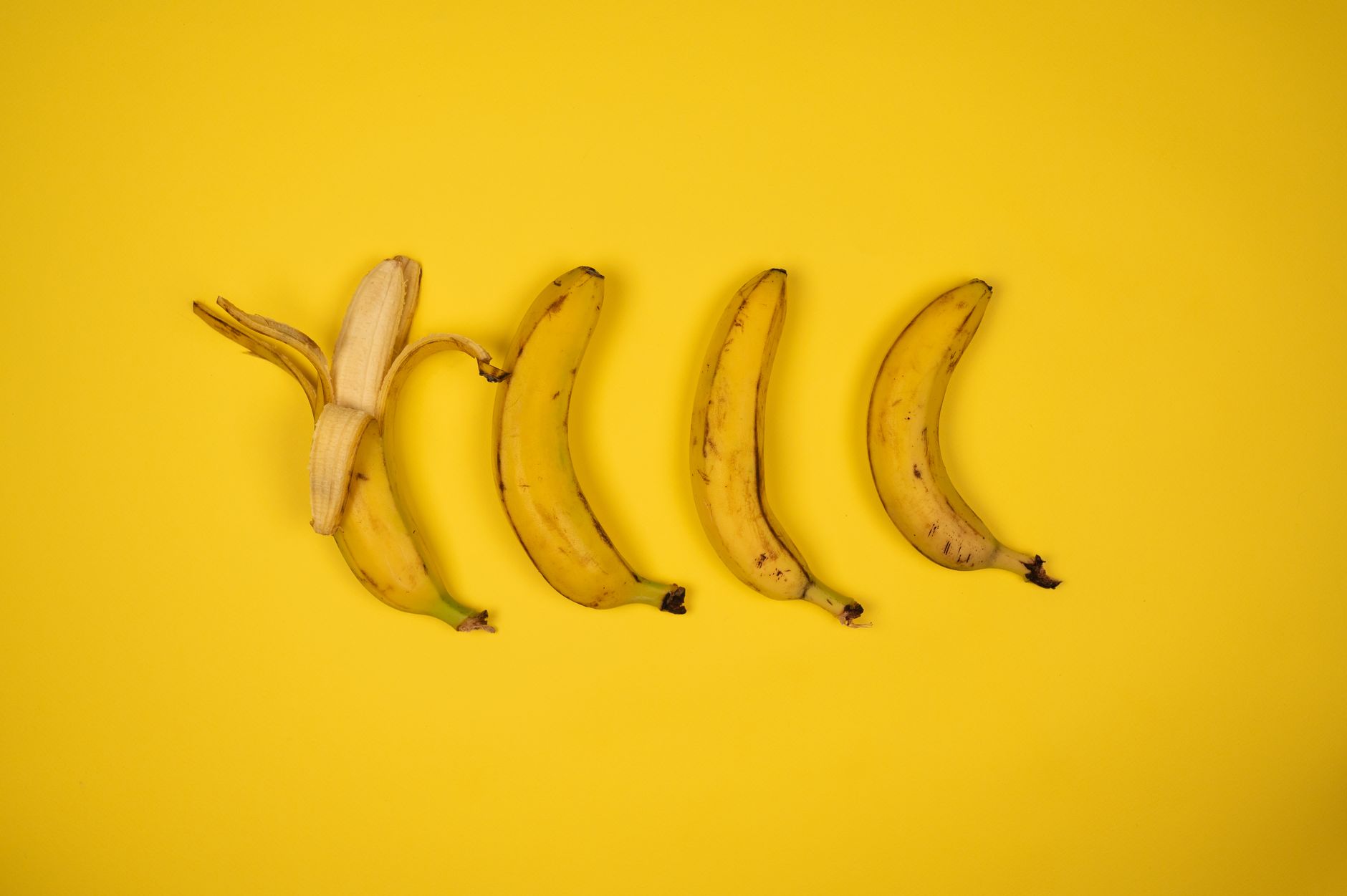 Overhead view backdrop of delicious sweet bananas in row with ripe flesh and spots on yellow peel