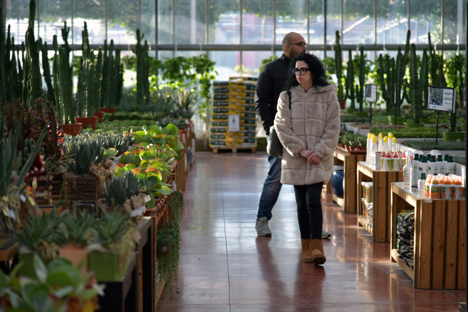 Shoppers browsing plants and gardening supplies in a well-lit indoor garden center.