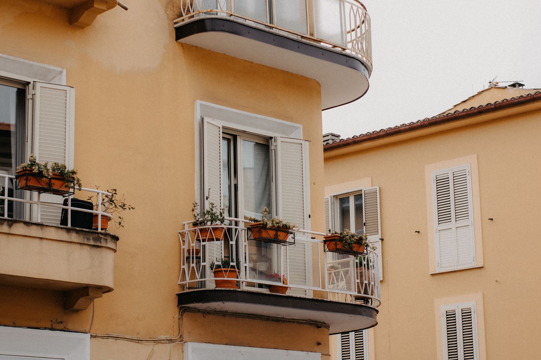 A close-up view of charming balconies adorned with potted plants on a yellow residential building.
