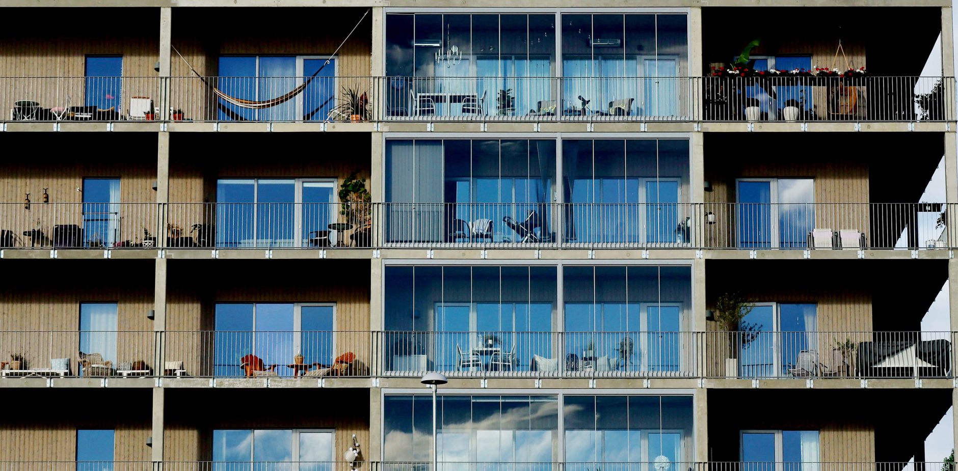 Facade of a modern residential building featuring glass windows, balconies, and metal railings.