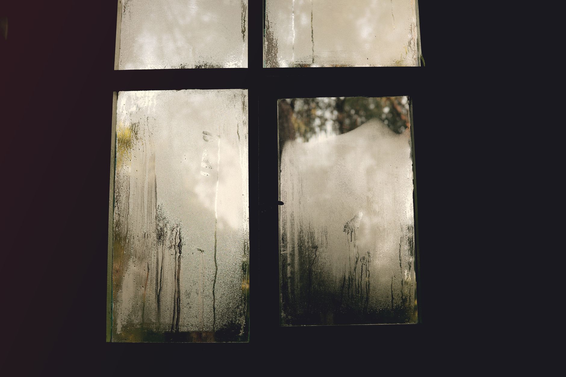 A foggy window pane with condensation, creating an abstract natural scene.