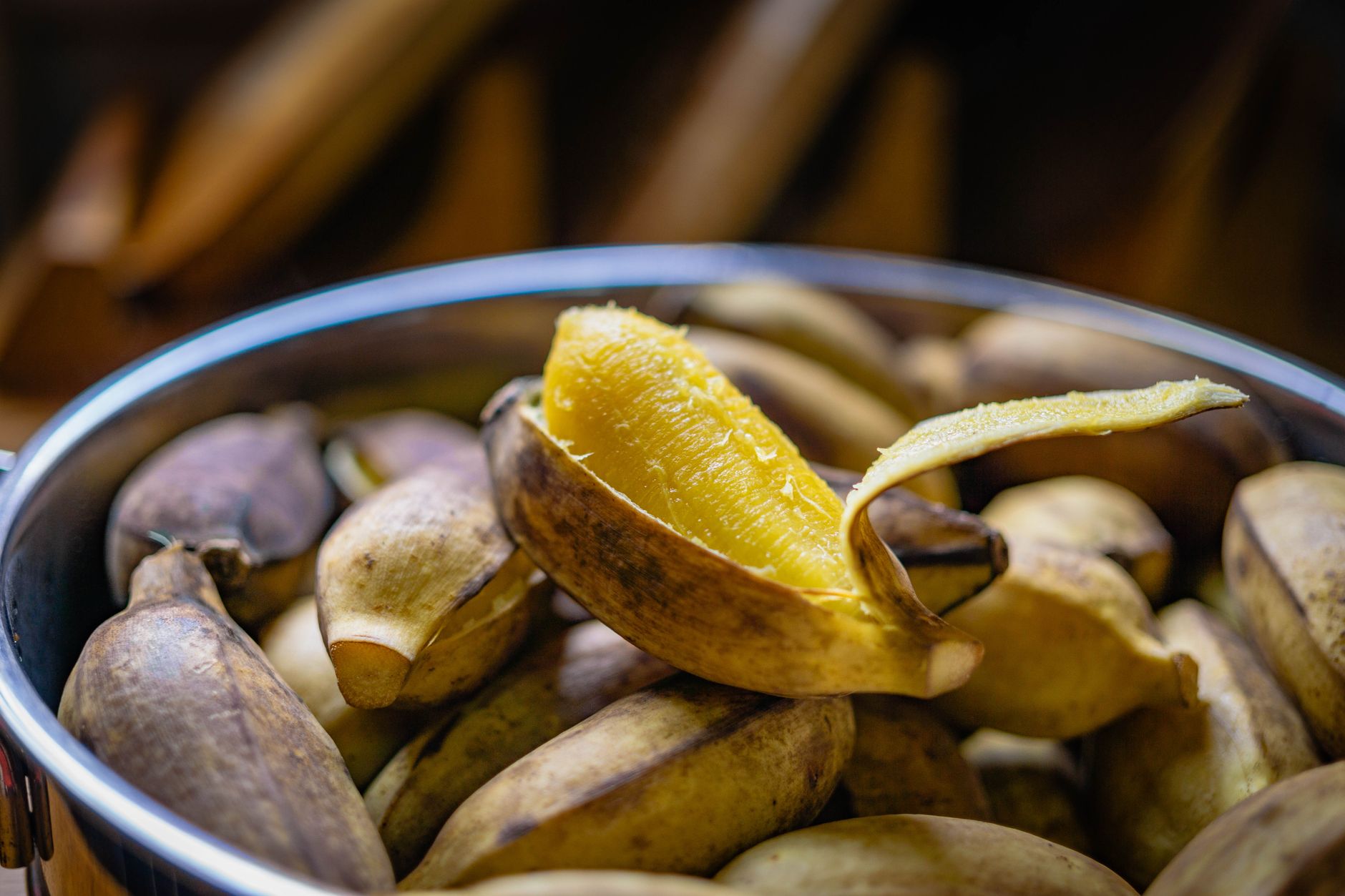 Vivid close-up image of ripe bananas in a shiny metal bowl, with vibrant colors highlighting the texture and freshness of the fruit.